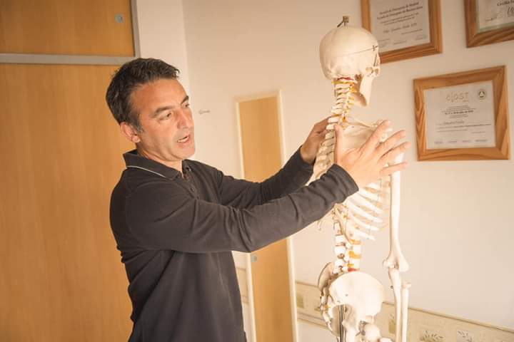 Consulta osteopática con modelo de columna en consultorio de Muñiz